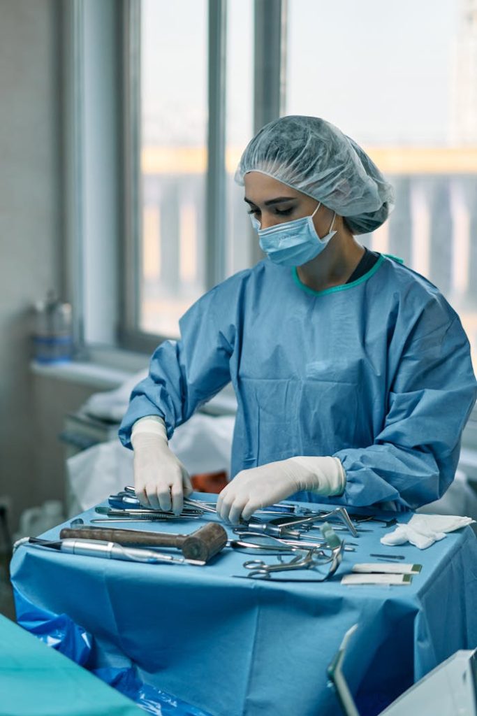 a-woman-arranging-medical-tools-in-an-operating-room-7583382 A female surgeon wearing protective gear arranges surgical instruments in a hospital operating room.